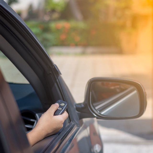 Hand of a person inside a car holding a remote control key